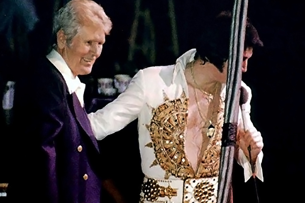 Elvis Presley stellt bei seinem letzten Konzert am 26. Juni 1977 in Indianapolis seinen Vater, Vernon Presley, dem Publikum vor – ein emotionaler Moment, der den tiefen familiären Zusammenhalt zeigt.